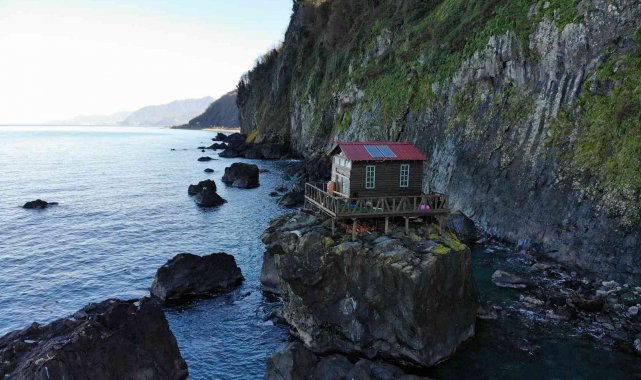 Deniz kıyısındaki kayanın üzerine yapılan baraka dikkat çekiyor