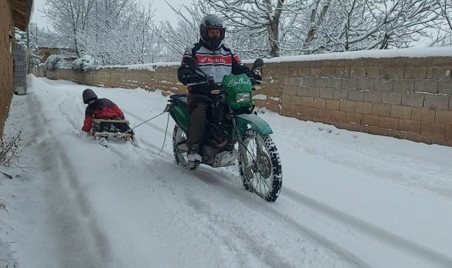 Motosiklete bağladığı kızaklarla çocukları karda eğlendirdi