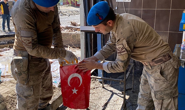 Komandolar çamurun altında buldukları Türk bayrağı ile Atatürk posterini yıkayıp öperek yeniden astı
